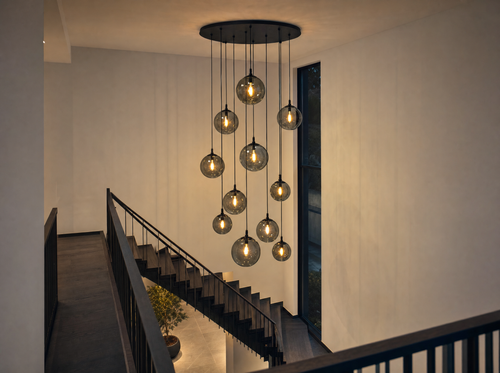 The smoked-glass globe chandelier hanging in a tall stairwell